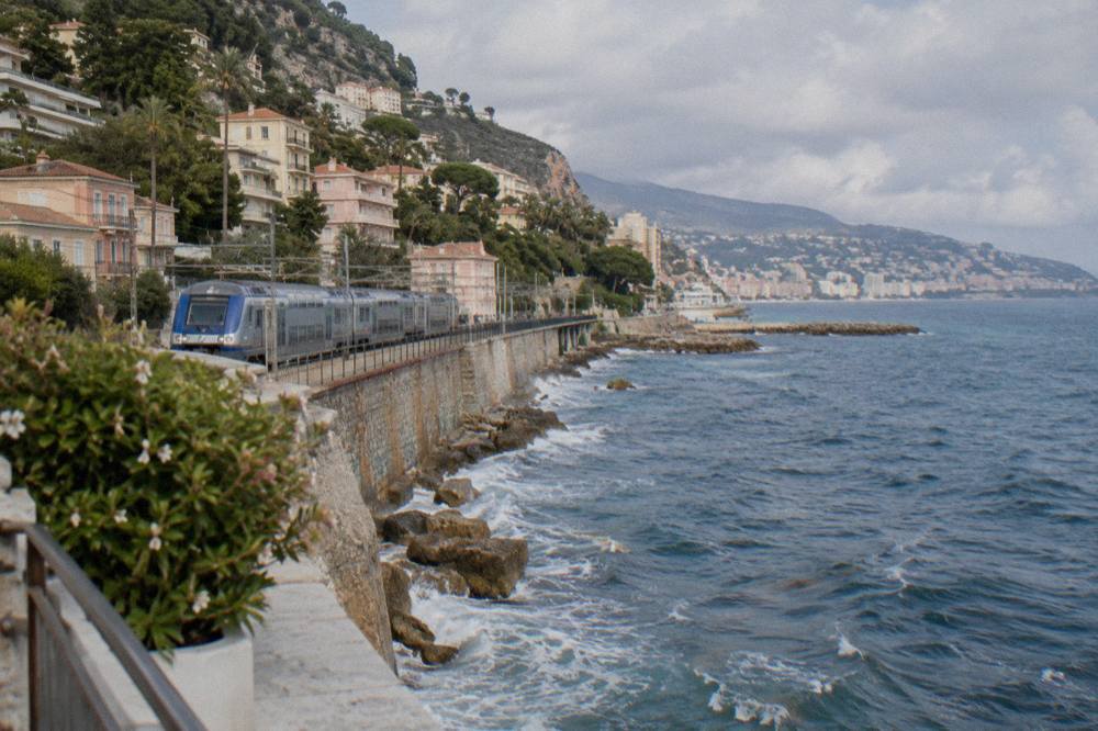 A regional train at a Riviera station platform with the sea in the background
