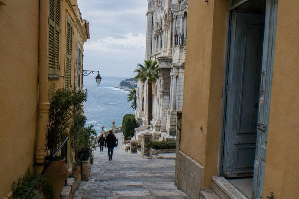 Narrow stone street on the Rock of Monaco with old buildings and a glimpse of the sea