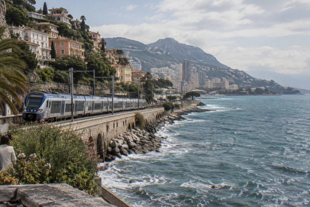 Train platform at Monaco station with modern carriages and travelers waiting