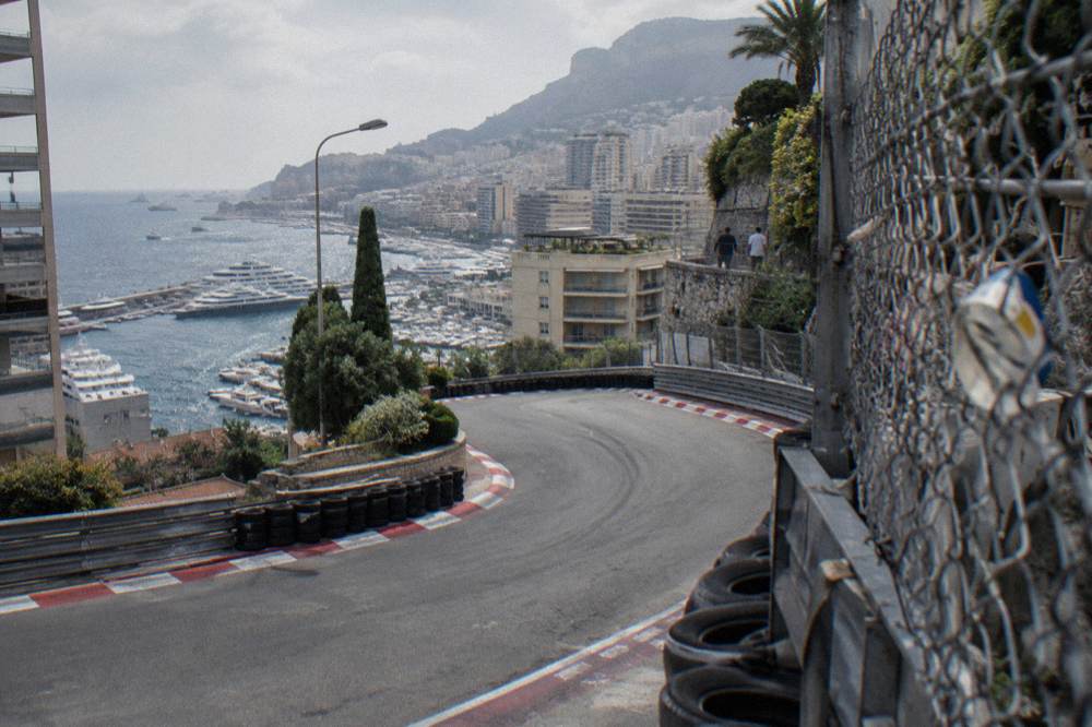 Grandstands and barriers along a street circuit with hills and buildings behind Monaco harbor