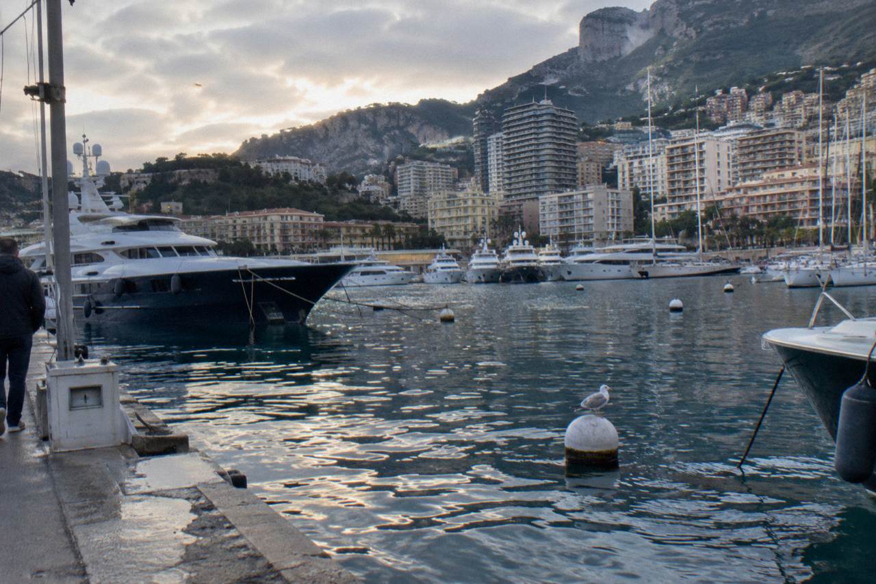 View over Monaco's harbor with hillsides buildings and moored yachts under a clear sky