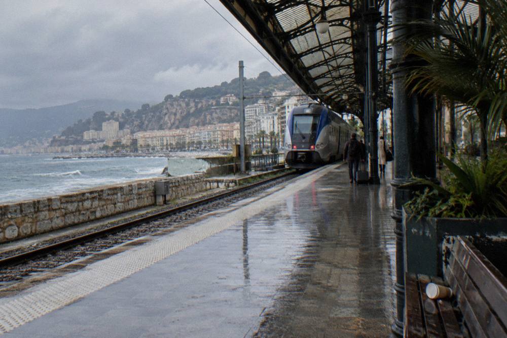 Train platform at a Mediterranean coastal station with the sea in the background
