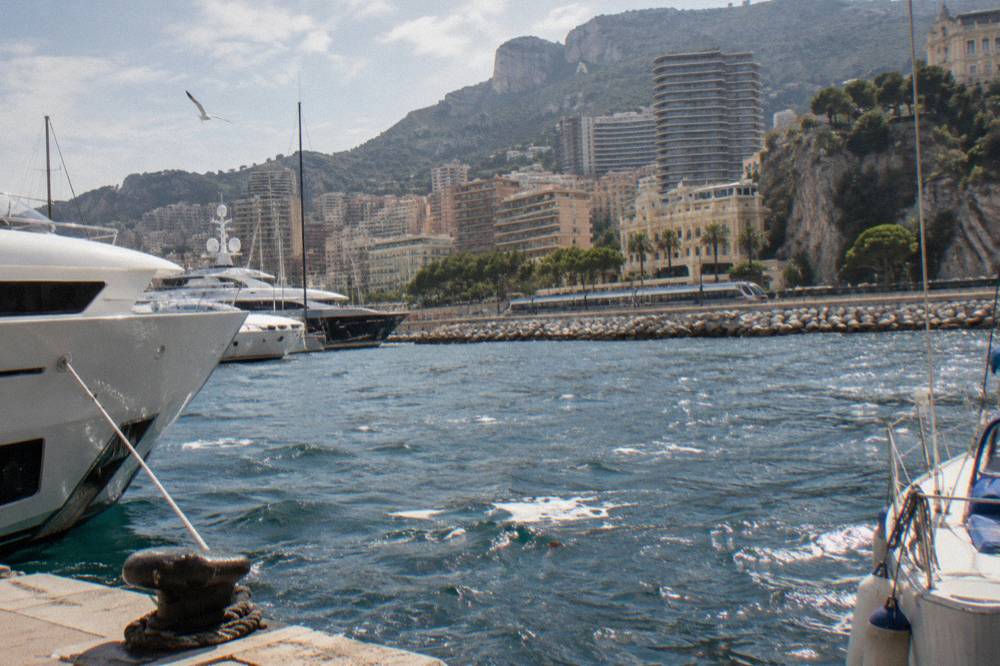 Regional train travelling along the Mediterranean coastline with steep cliffs and apartment buildings above the water