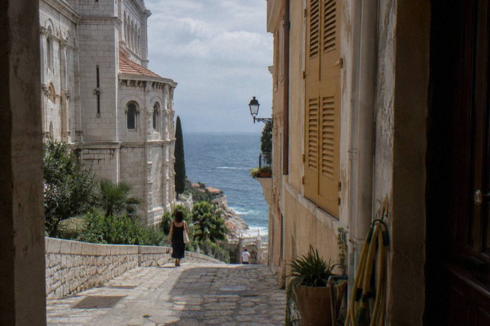 Narrow stone street on the Rock of Monaco with old buildings and a glimpse of the sea between walls