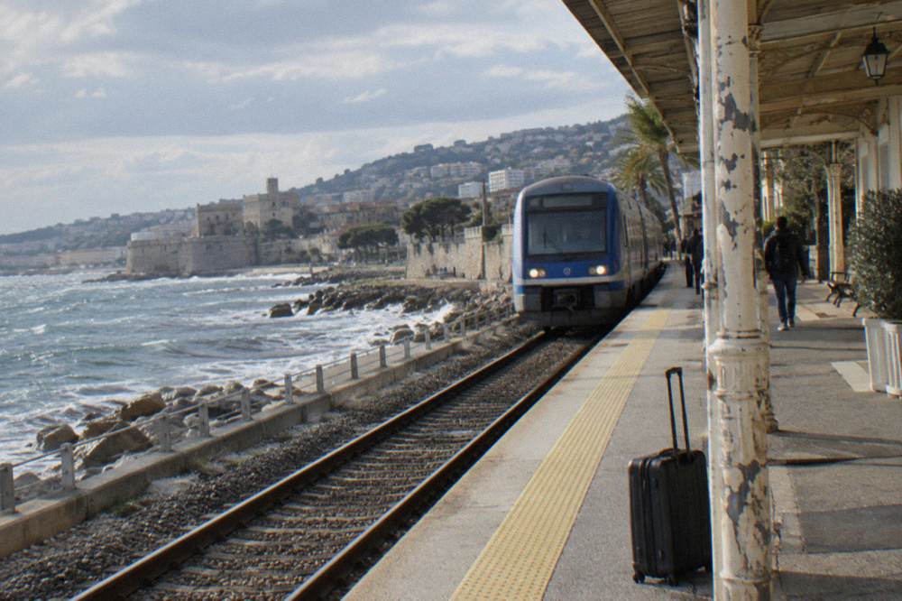 Blue regional train arriving at a station platform on the French Riviera coast