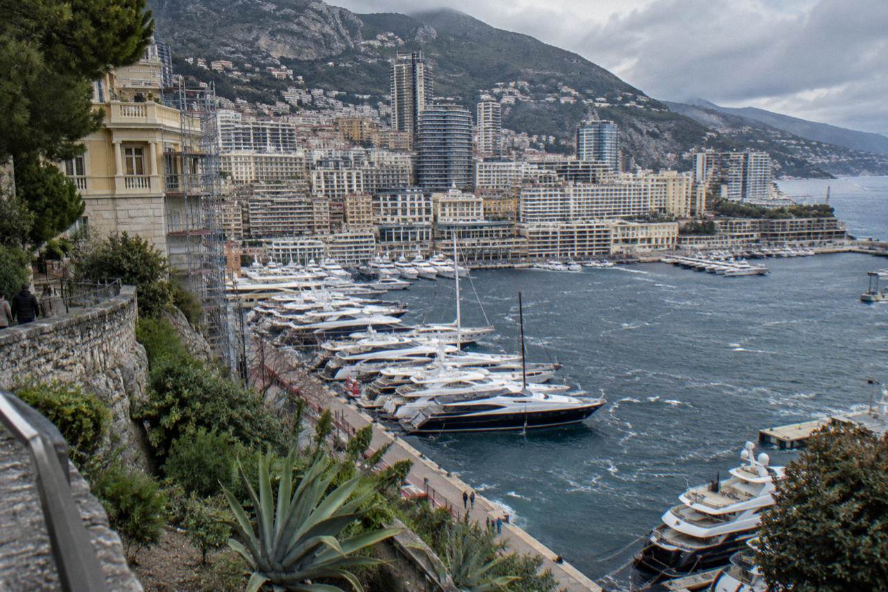 View over Monaco harbor with luxury yachts moored along the quays and hillsides rising behind the port