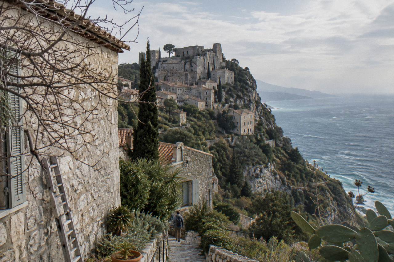 Stone medieval village buildings rising on a hilltop above the Mediterranean sea