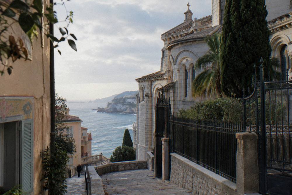 Narrow stone street on the Rock of Monaco with old buildings and a glimpse of the sea
