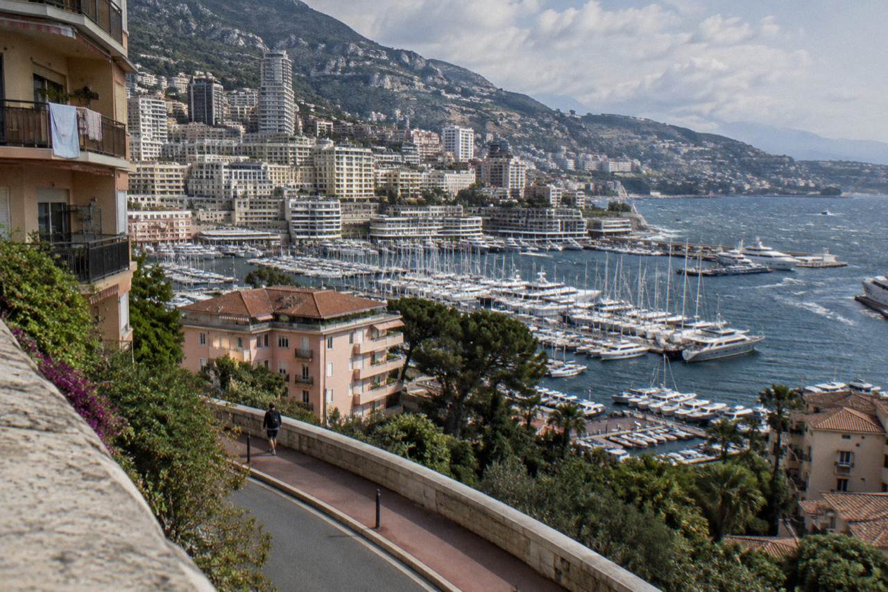 View over Monaco harbor with yacht moorings and hillside buildings under a clear sky