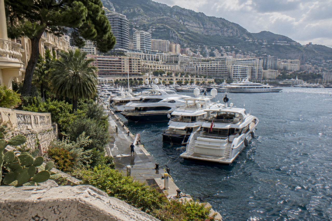 Harbor of Monaco with luxury yachts moored along the quay and hillsides rising behind the port