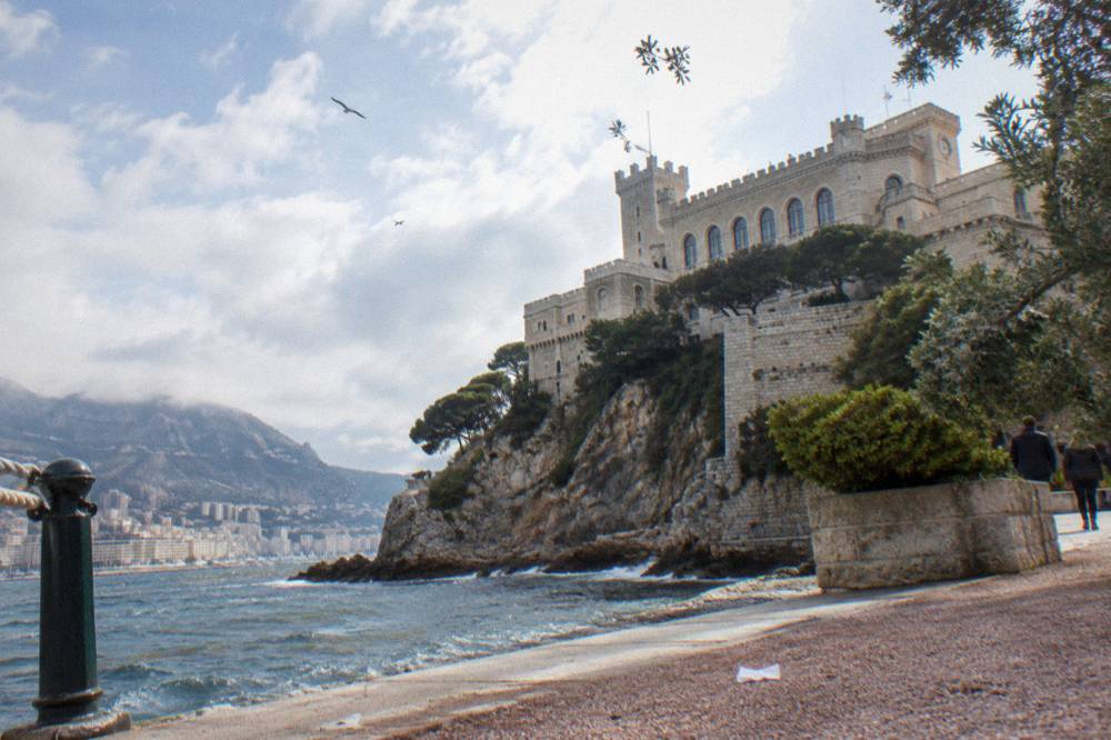 Stone palace facade on a rocky promontory above a Mediterranean town