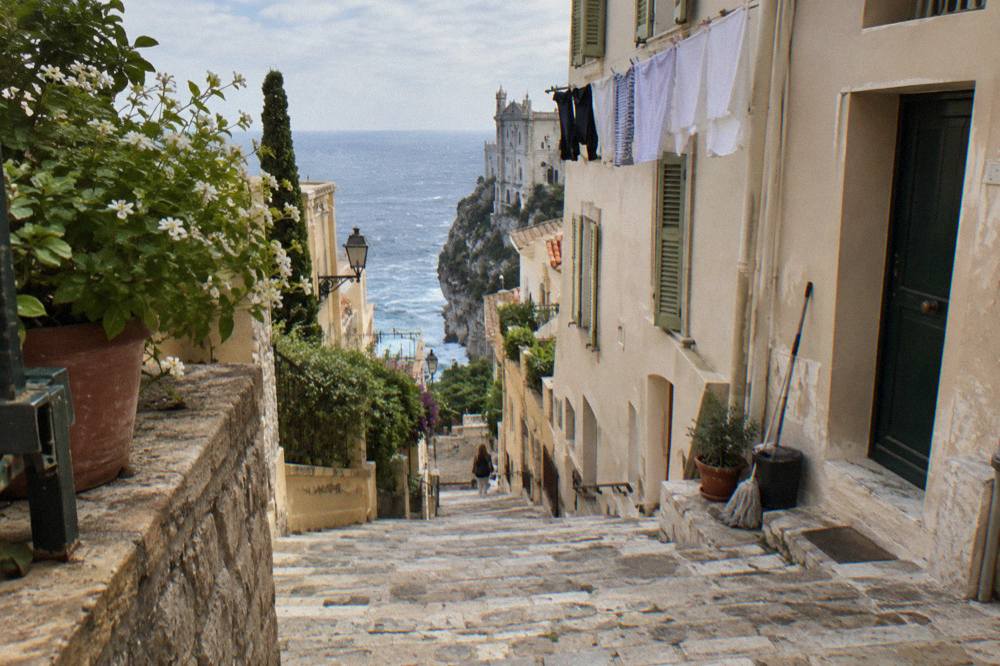 Narrow stone street on the Rock of Monaco with old buildings rising above the sea