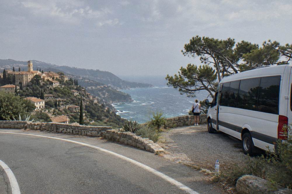 Tour van parked on a coastal road above the Mediterranean near Eze