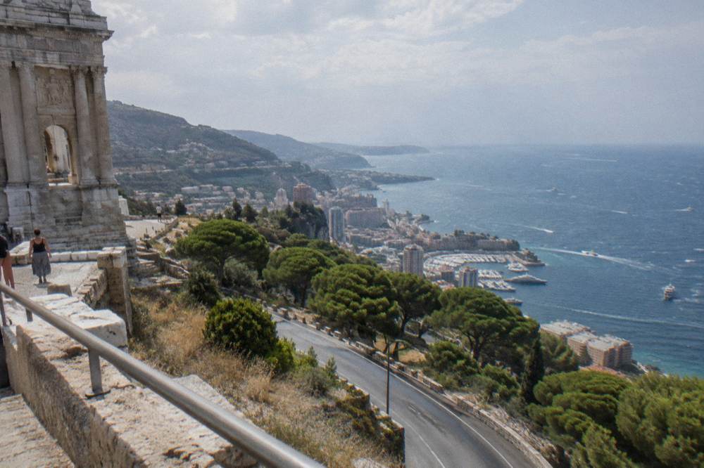 Coastal road curving between Nice and Monaco with pine trees, apartment blocks and the blue Mediterranean beyond