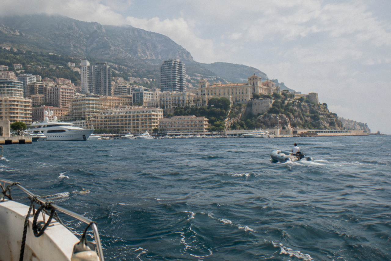 Overlook above the Mediterranean with Monaco's harbor, hilltop old town and tall apartment buildings beneath a clear sky