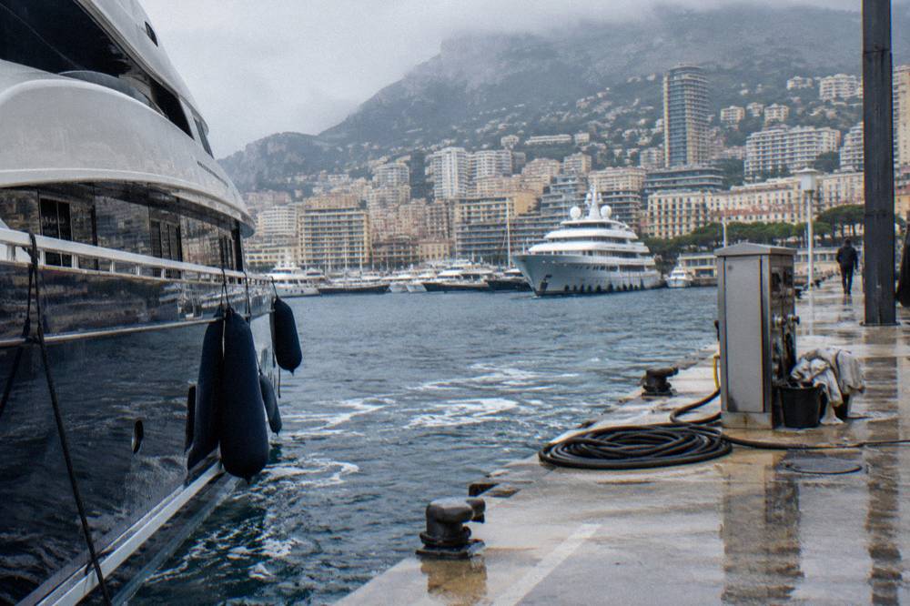 The Monaco harbor with luxury yachts moored along the quays and hillsides behind