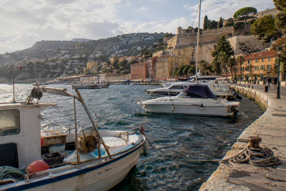 Yachts moored in a small harbor with a walled old town behind