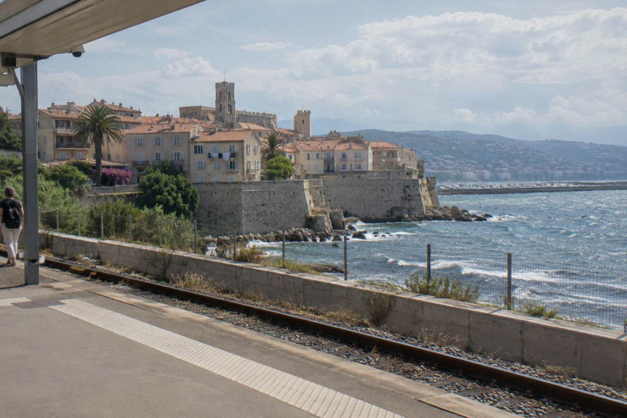Old town rooftops and a Mediterranean bay with hills rising along the coast