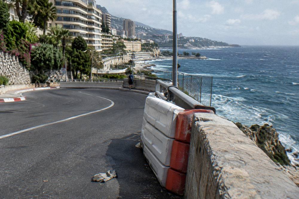 A Mediterranean coastline road curving along cliffs above a blue sea.