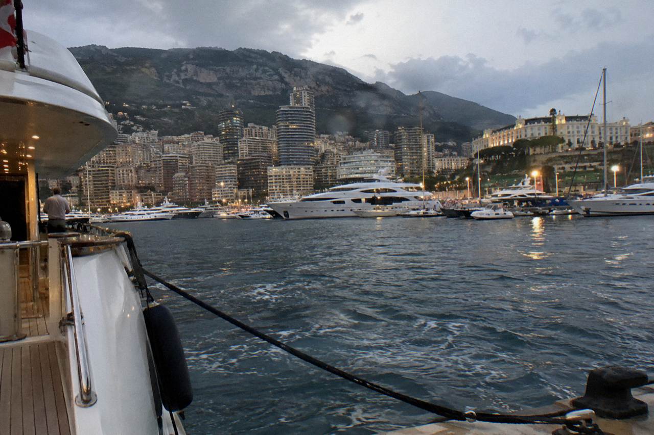 The Monaco harbor front with luxury buildings rising behind the yacht-filled port.