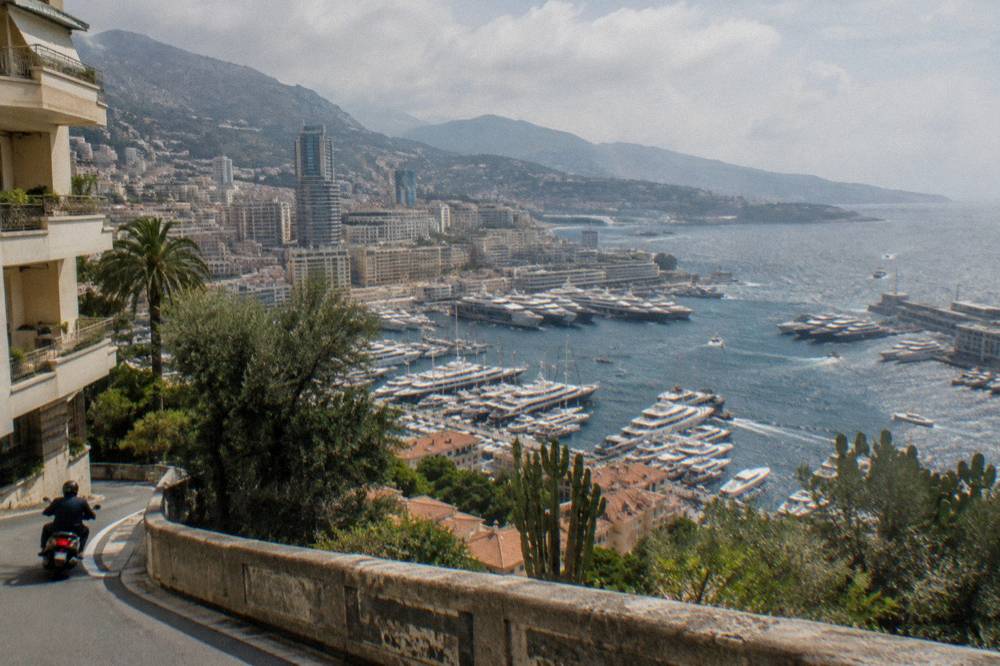 Harbor filled with yachts and luxury boats seen from a hillside road