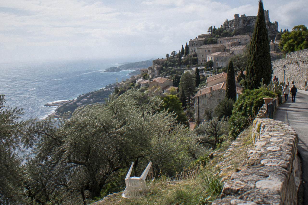 Stone medieval village buildings rising on a hillside above the Mediterranean