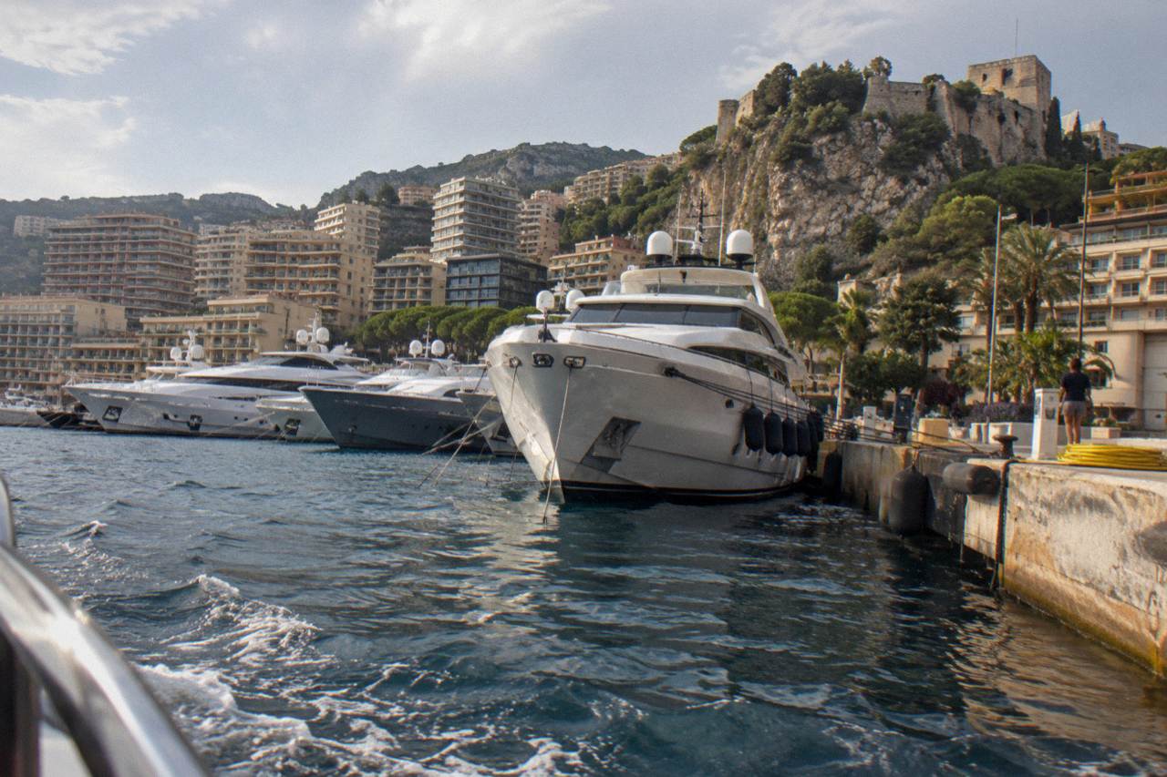 Yachts moored in Port Hercule with the cliffs of the Rock of Monaco rising behind them