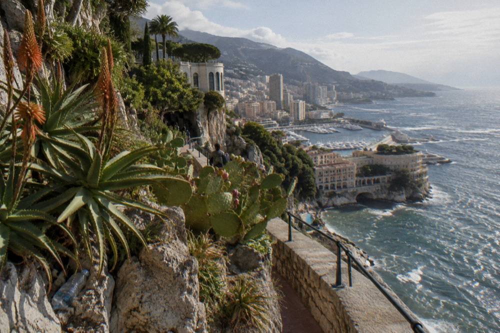 Coastal road curving along a cliff above harbors and a densely built shoreline