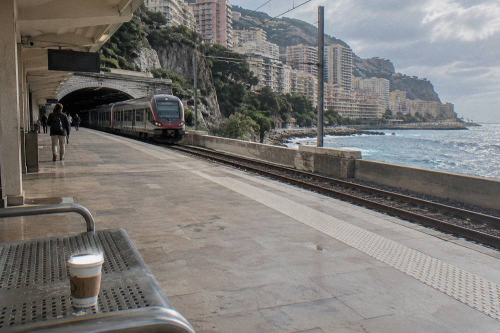 Train platform at Monaco station with the hillside town visible beyond the tracks
