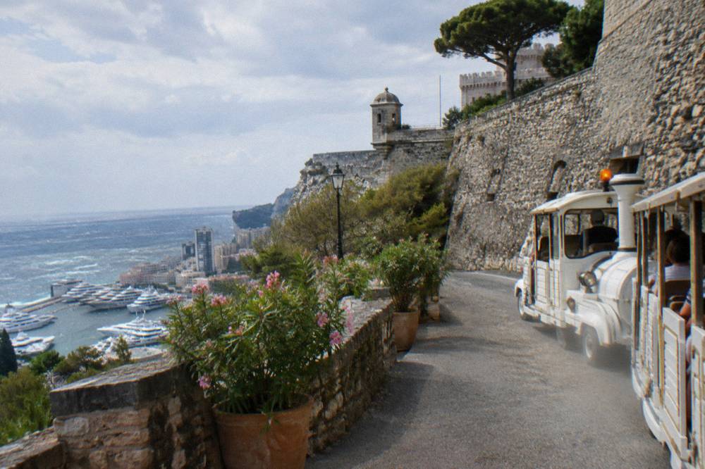 Small road tourist train on a narrow street below the Monaco old town walls