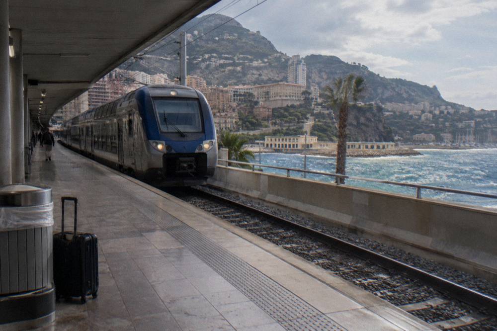 TER regional train arriving at Monaco station platform with hills in the background