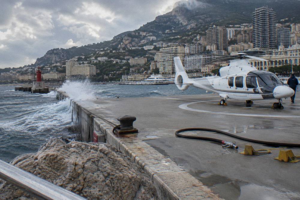 Helicopter on a seaside helipad with apartment towers and hills in the background