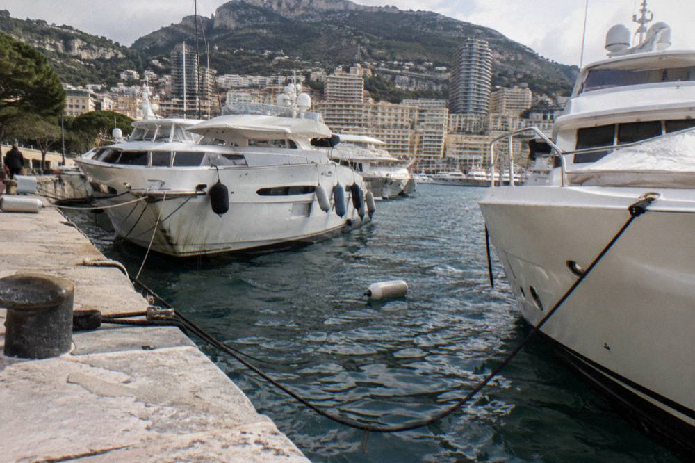 Harbour at Monaco with yachts moored along the quay beneath steep hillsides in soft winter light