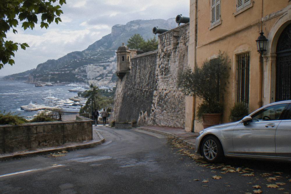 Luxury sedan waiting on a narrow street beside Monaco's old town walls