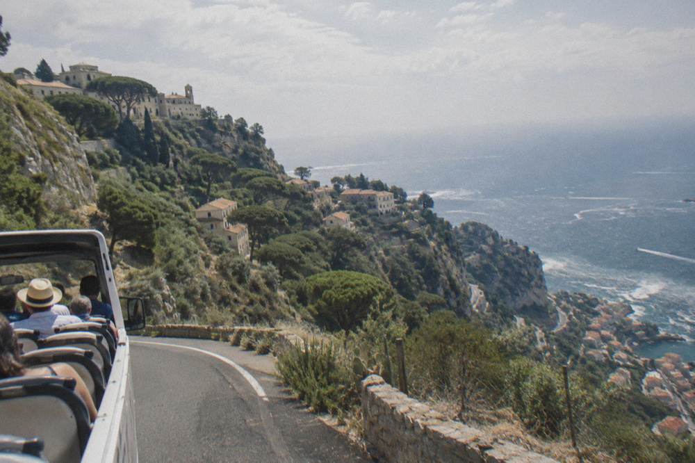 Open-top tour van driving the corniche road high above the Mediterranean