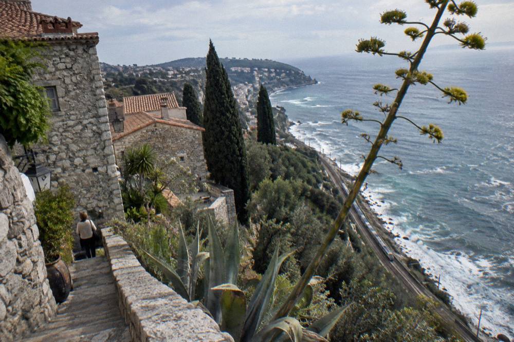 Hillside village with stone buildings overlooking the Mediterranean and a coastal railway below