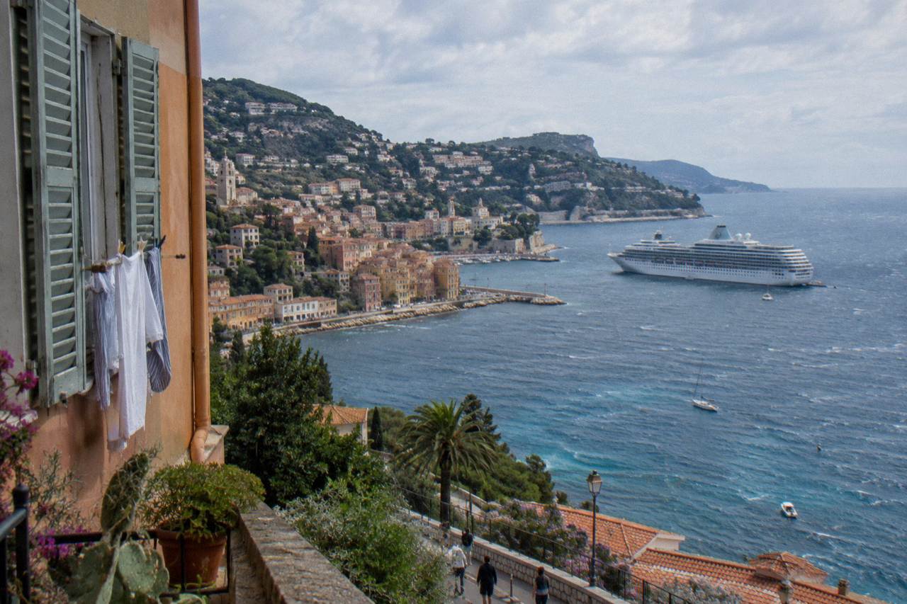 Cruise ship anchored in a Mediterranean bay with a hillside town above the water