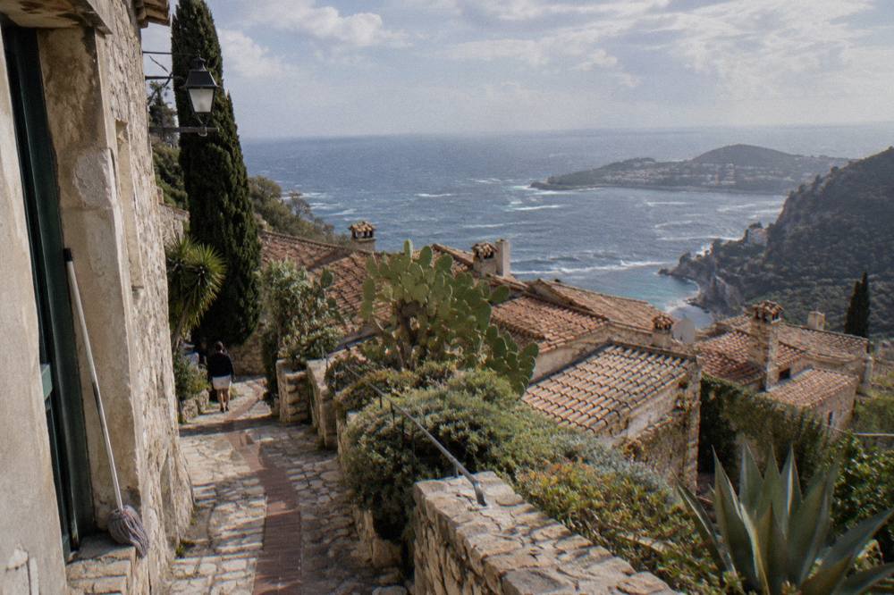A stone alley in a hilltop village with terracotta roofs above the sea