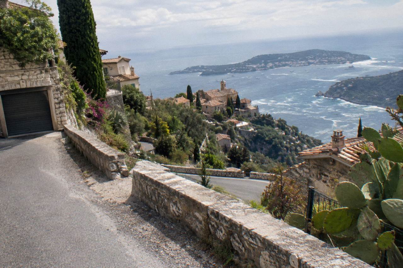 A winding cliffside road above Mediterranean rooftops leading toward Monaco