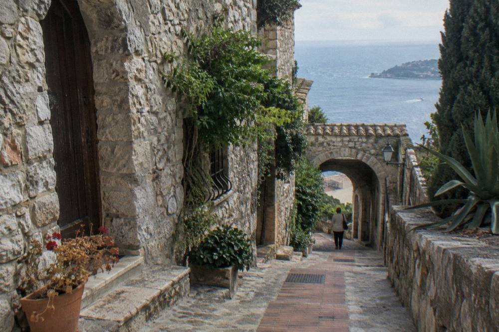 Narrow stone street in Eze Village with Mediterranean in the distance