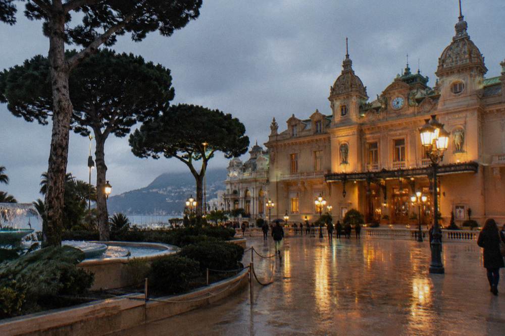 Monte Carlo Casino facade at dusk with lit lamps and Belle Epoque architecture
