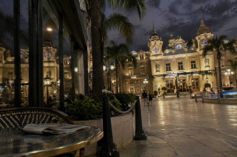 Casino de Monte-Carlo facade lit at night with palms and empty square