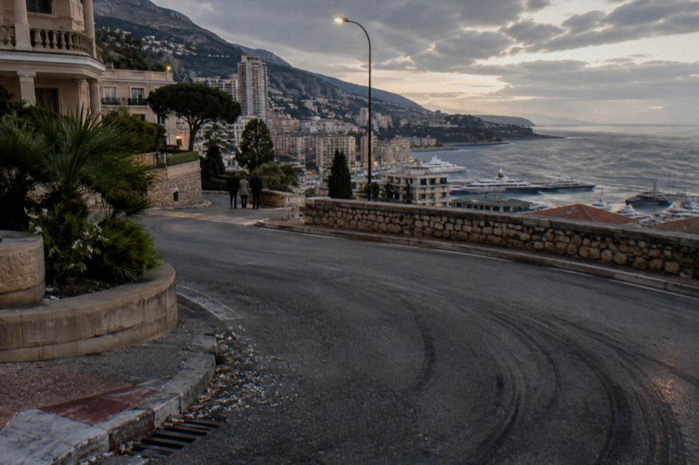 Coastal road at dusk with headlights tracing the corniche above the sea