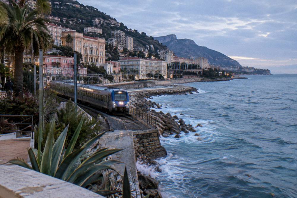 Monaco train station platform lit at night with a waiting regional train