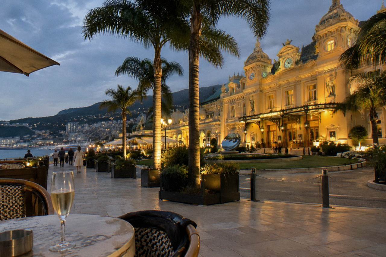 Illuminated Casino de Monte-Carlo and Cafe de Paris terrace glowing after dark