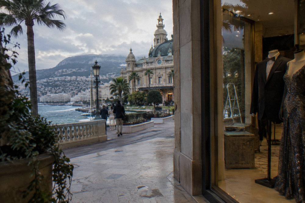 Evening gowns and dark suits displayed in a Monte Carlo boutique window