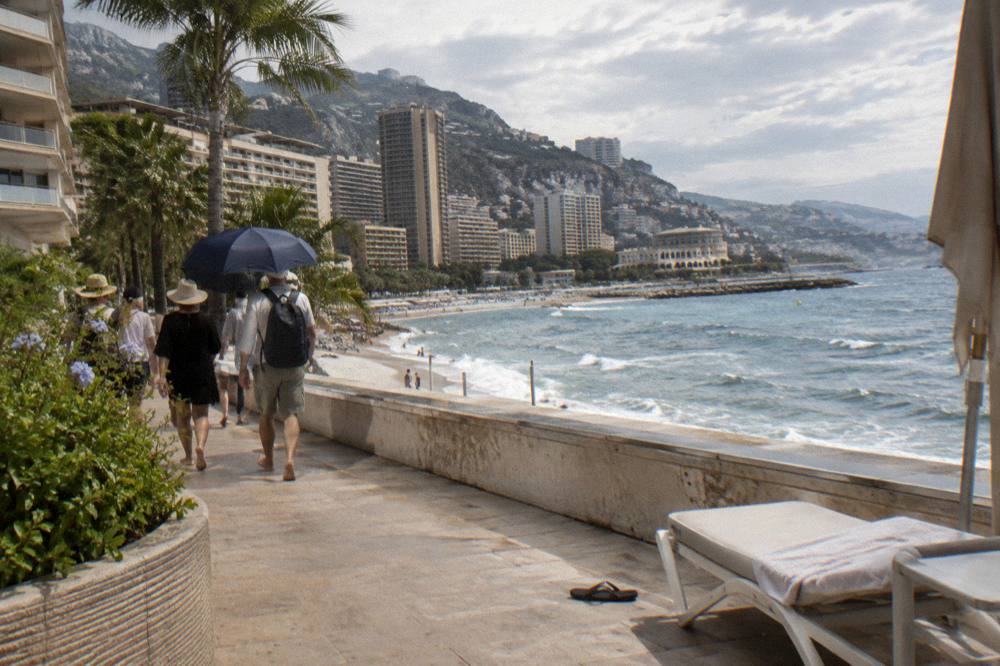 Small group of travelers following a guide along a Monaco seafront promenade