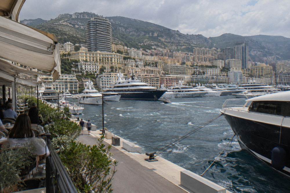 Superyachts moored in Port Hercule seen from above with Monaco buildings climbing the hillside