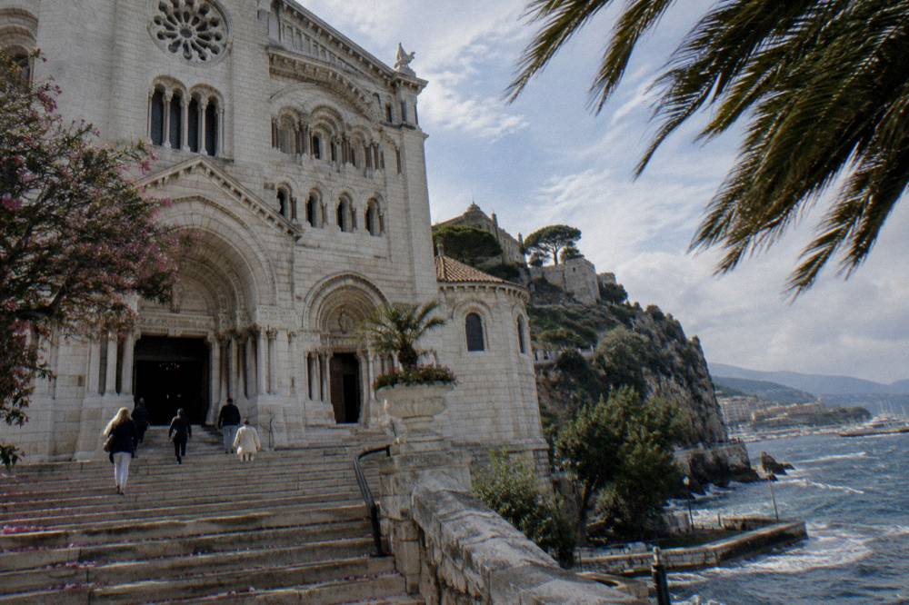 Stone facade of Monaco Cathedral with the palace walls above on the Rock