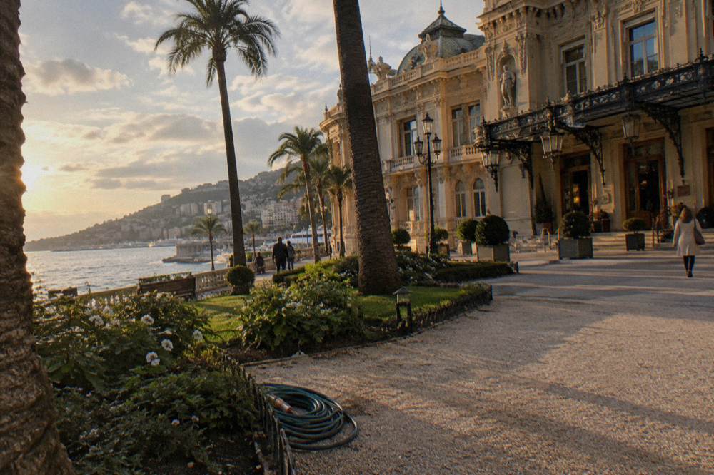 Ornate facade of the Casino de Monte-Carlo across a planted square at golden hour